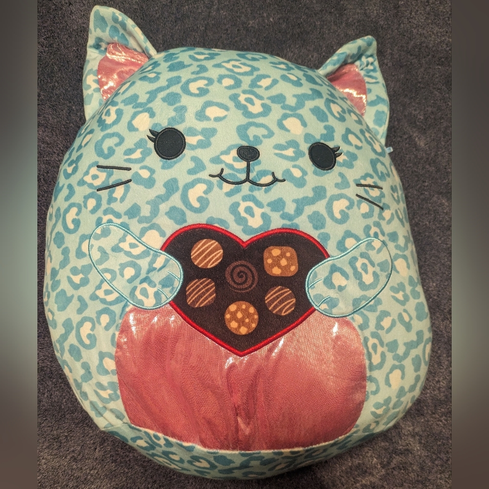 Blue and pink leopard Squishmallow holding a heart of chocolates.
